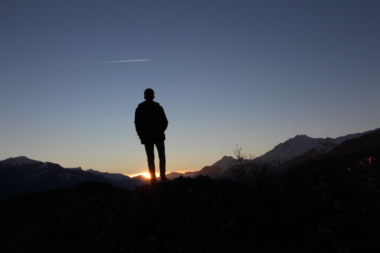 service-01 Person silhouette on mountain during sunset, capturing peaceful moment.